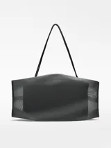 Bolso negro de malla con bolsa interior de piel y forro de algodón orgánico. Tiene cierre de cremallera lateral, asa corta fija y etiqueta exterior con logo.