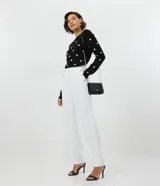 Pantalón wide leg blanco confeccionado en crepé, con botones dorados en los laterales, bolsillos y cierre con botón y cremallera.