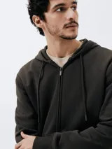 Campera marrón unisex con capucha y cierre frontal, confeccionada en algodón con felpa, corte regular fit y bolsillos tipo canguro.