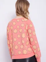 Buzo de tela deportiva, color celeste, con estampado de caritas felices en toda la prenda, de manga larga y cuello redondo.