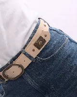 Cinturón de cuero color beige con hebilla ovalada y apliques metálicos color bronce.