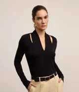 Blusa negra de mangas largas confeccionada en viscosa, con cuello alto, escote V y aberturas en los hombros.