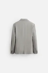 Blazer regular fit color gris claro confeccionado en tejido con lana. Tiene cuello con solapas de muesca, manga larga con puño abotonado, bolsillo de vivo en el pecho, bolsillos de solapa en la cadera, bolsillo interior, aberturas en la espalda y cierre frontal con botones.