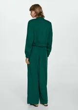 Pantalón verde esmeralda de corte ancho con pinzas, trabillas y cinturón decorativo con hebilla metálica.