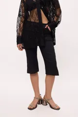 Pantalón capri negro con terminación en picos y costuras en color ladrillo.