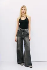 Jean oxford tiro alto de denim negro con lavado stone y bigotes. Pierna ancha desde la cadera.