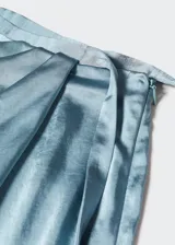 Falda midi cruzada color celeste, de tejido satinado y fluido, con abertura lateral, cierre lateral de cremallera, tiro medio, detalle fruncido y cierre de lazo lateral.