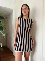 Vestido corto de algodón tejido en punto jersey con diseño de rayas verticales rojas y blancas. Terminaciones en crochet hechas a mano con detalle de lurex. Cuello redondo, sin mangas y silueta trapecio.