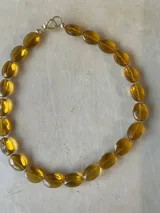 Collar de cuentas ovaladas facetadas color ámbar, con cierre de mosquetón dorado.