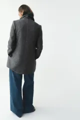 Abrigo corto gris jaspeado con cuello solapa y manga larga. Cierre frontal con botones.