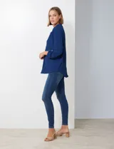 Blusa de gasa color beige, con cuello a la base y escote en V. Manga larga con presilla y botón para ajustar el largo.