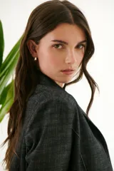 Blazer de mujer color gris oscuro con textura de jean/lino, corte oversize, hombreras, bolsillos frontales y pespuntes a contratono. Cierre frontal con botones.