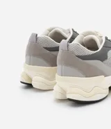 Championes dad sneaker grises con recortes en cuero sintético, cordones blancos y suela chunky de goma color crema.