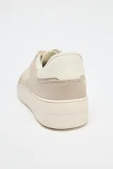Zapatillas deportivas color beige, con suela alta de 3 cm y cierre con cordones.