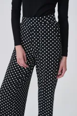 Pantalón de tiro alto, corte recto y largo, con estampado de lunares blancos sobre fondo negro.