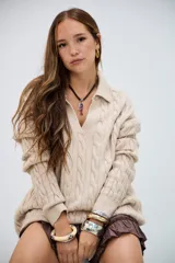 Sweater de punto trenzado color beige, con cuello en V y cuello polo, de manga larga y corte holgado.