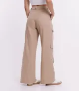 Pantalón cargo de sarga color beige, corte sastrero, con cintura alta, trabillas, cierre con botón y cremallera, y bolsillos laterales tipo cargo.