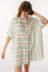 Camisa de lino a rayas verticales en colores pastel: blanco, verde, lila, naranja y celeste. Tiene cuello mao, manga corta con puño, botones de metal a la vista, ruedo camisero y tajos laterales.
