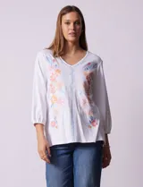 Blusa blanca de algodón con bordado de flores en tonos pastel y mangas 3/4.