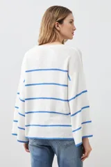 Sweater de punto color blanco con rayas horizontales azules, de corte holgado y mangas largas acampanadas.