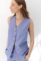 Chaleco gris con finas rayas verticales blancas, con cuello en V, cierre frontal con botones y bolsillos laterales.