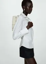 Camisa blanca de popelina de algodón, corte clásico, con cuello camisero, cierre de botones y detalles fruncidos.