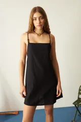 Vestido corto negro con tirantes finos y escote cuadrado. Toda la superficie del vestido está cubierta con pequeñas aplicaciones de pedrería.