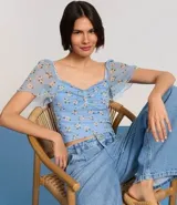 Blusa cropped de tule celeste con estampado floral, escote corazón, mangas cortas sueltas con acabado frufru y fruncido en el busto.