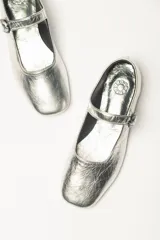 Zapato estilo Mary Jane color marrón, de cuero, con punta redondeada y tira sobre el empeine con hebilla.