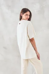 Remera de algodón color crudo, de corte oversize, con estampado de una manga y texto en portugués.