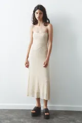 Vestido midi de encaje color crudo, con escote recto y hombros descubiertos. Detalle de tira con lazo combinada a tono. Forro interior y cierre lateral con cremallera oculta en costura.