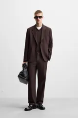 Blazer color borgoña de corte regular, con cuello de solapas de muesca, manga larga con puños abotonados, bolsillos de doble vivo en la cadera, bolsillo interior, abertura en el centro de la espalda y cierre frontal con botonadura.