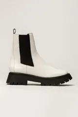 Bota Chelsea color verde militar de cuero, con elásticos laterales negros, tirador trasero y suela track negra.