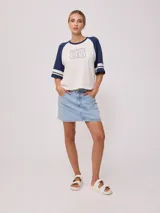 Remera bicolor Rusty con cuerpo verde lima y mangas ranglán grises con dos rayas blancas en los puños. Estampado frontal con el logo de la marca y el número 85.