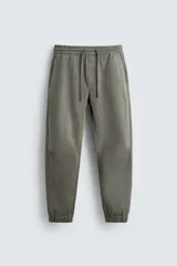 Pantalón jogger color verde oliva, corte slim fit, confeccionado en tejido de algodón con cintura elástica ajustable con cordón, bolsillos frontales y traseros de vivo, bajo acabado en puño con elástico.