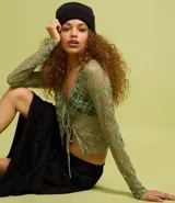 Blusa verde de encaje floral transparente, con escote en V y lazos delanteros.