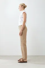 Pantalón recto color tostado con pespuntes verticales y cinturón de cuero marrón con hebilla dorada.