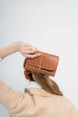 Billetera tipo sobre de cuero negro con cierre de elástico, separaciones internas y bolsillo con cierre para monedas.