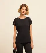 Remera deportiva negra de manga corta confeccionada en microfibra de poliamida ligera con agujeritos en los hombros y bieses en contraste color naranja en las sisas.