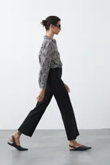 Pantalón negro de tiro alto, corte recto y silueta clásica. Presenta costuras verticales marcadas en la parte delantera de las piernas.