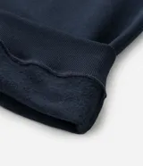 Buzo de manga larga color azul marino, confeccionado en tejido de algodón con felpa, con cuello polo blanco contrastante y abertura frontal con botones.