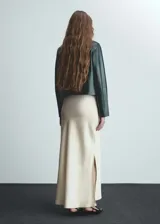 Falda maxi color crema de tejido satinado con goma elástica en la cintura y abertura lateral.