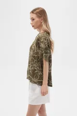 Blusa verde militar con estampado de flores blancas, de viscosa, corte holgado, cuello redondo y mangas cortas.