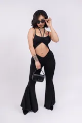 Mono enterizo negro ajustado al cuerpo, con escote halter y abertura en el abdomen.