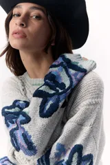 Sweater tejido de punto gris con diseño de flores bordadas en las mangas, cuello a la base y calce recto.