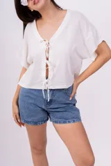 Remera color amarillo pálido de corte holgado, escote en V con lazo y mangas cortas.