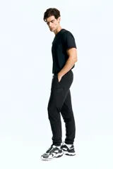 Pantalón de jogging deportivo negro de corte ajustado, confeccionado en tejido funcional DryMove™ que absorbe el sudor. Cuenta con cintura elástica con cordón de ajuste, bolsillos laterales, bolsillos con cierre en las piernas y bajos elásticos.