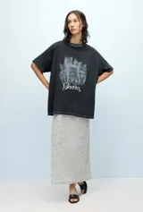 Remera negra de jersey de algodón peruano, con calce oversize, escote a la base y mangas cortas. Presenta un estampado de gatos y la palabra 'Ginebra' en el frente.