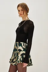 Falda corta con volados, tiro alto, confeccionada en tejido lurex con estampado abstracto en tonos verde oscuro y dorado.