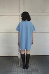 Vestido camisero celeste de denim con botones frontales, mangas cortas, cuello camisero y bolsillos cuadrados.